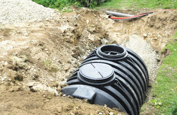 A black septic tank halfway buried in dirt outside